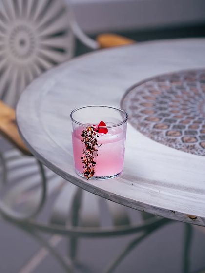 A romantic gin cocktail, crafted with citrus, honey water, and the essence of carmine roses. A potent tale of love in a glass.