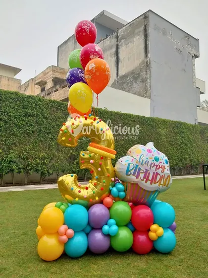 A vibrant and colorful balloon bouquet for a 3rd birthday. The gold number '3' is surrounded by a rainbow of balloons and a fun cupcake foil balloon, making it a pure expression of joy.