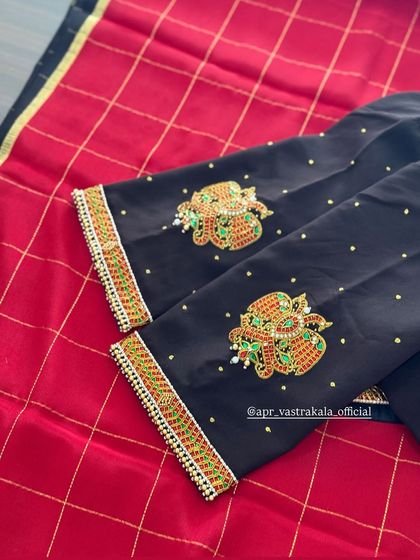 A flat-lay of the black kemp work blouse, showing the contrast between the dark fabric and the vibrant embroidery.