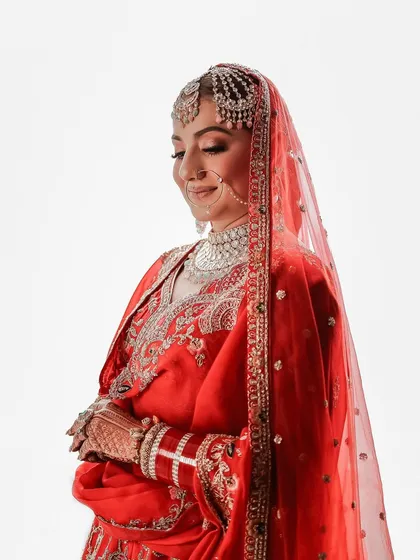 A serene and graceful portrait of the bride against a clean white background. This high-key shot emphasizes her beautiful features, jewelry, and the delicate details of her veil.