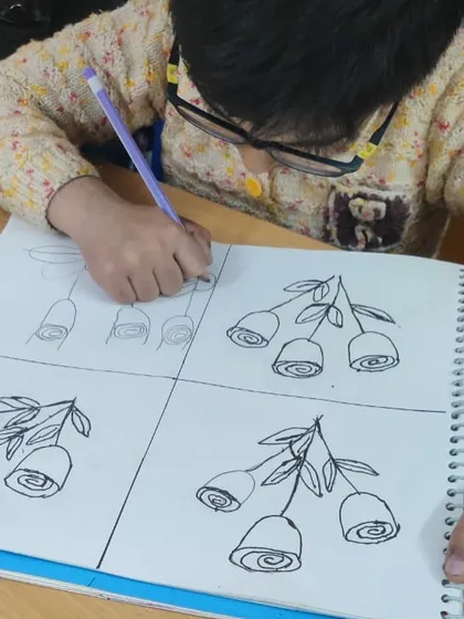 This worksheet shows how we teach drawing in a structured way. The student is practicing how to draw a rose step-by-step, from simple swirls to a complete flower.