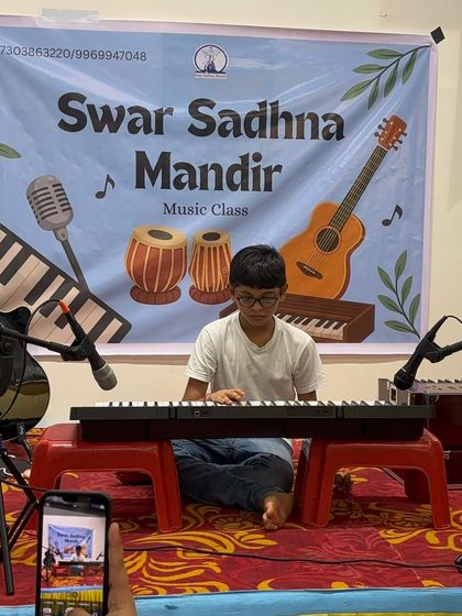 A student performs on his keyboard, with his proud parent capturing the moment. We love seeing families support our young musicians on their journey.
