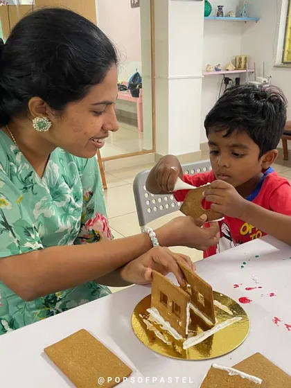 A mother helps her son assemble the walls of his gingerbread house, the first step in this fun, edible construction project.