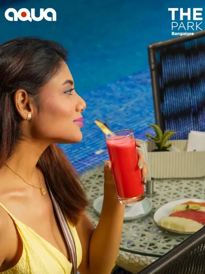 A guest enjoys a refreshing, vibrant cocktail by the pool at Aqua. Our drinks are ingredient-driven and contemporary, designed to perfectly match the relaxed, stylish vibe of our poolside bar.