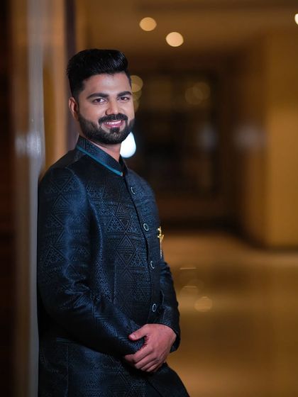 A confident portrait of the groom. The lighting highlights the subtle texture of his jacket and his flawless makeup.