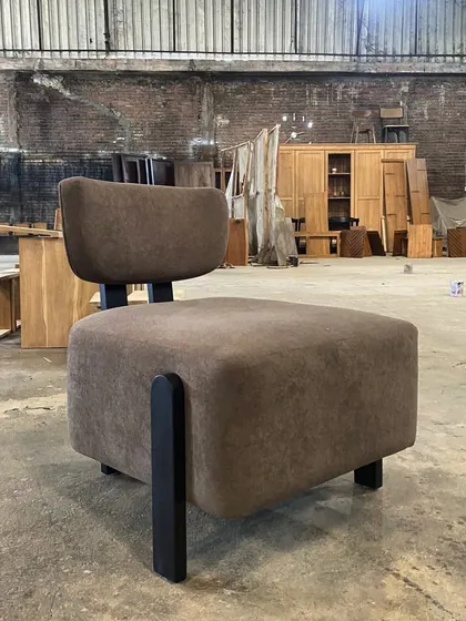 A minimalist lounge chair with a blocky, upholstered seat and a simple, low-profile backrest. This piece is perfect for modern and contemporary interiors.