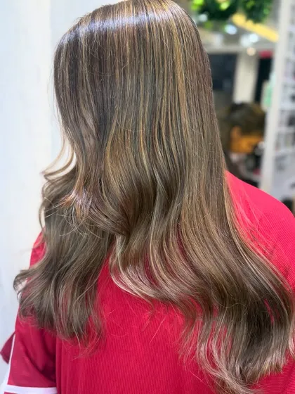 The back view of this milk tea brown hair shows the beautiful blend of blonde and brown tones. The soft waves add texture and highlight the color's dimension.