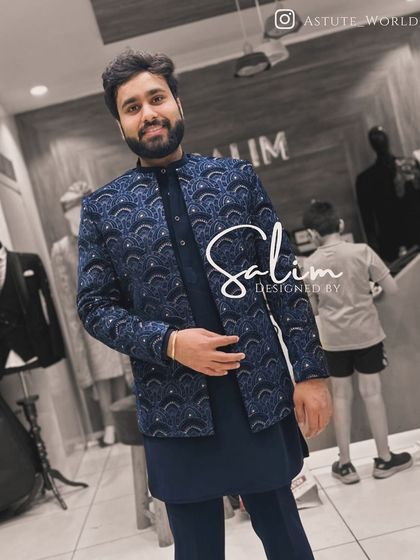A client smiling in a navy blue Indo-Western jacket with a subtle all-over geometric pattern. It's a versatile piece that can be dressed up or down for various occasions.