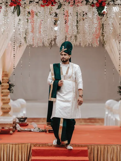 The groom's entrance is a statement. Here, we captured the groom in his regal attire, standing confidently on the stage, ready to begin a new chapter. It's a shot that speaks of anticipation and style.