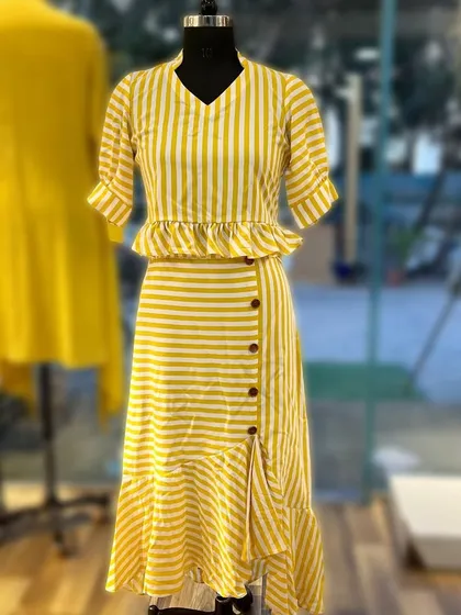 This charming yellow and white striped cotton set features a peplum top and a matching ruffle skirt with a side slit. It's a fun, breezy outfit that is perfect for a summer day out.