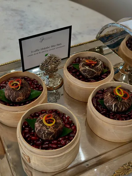Our Truffle Shiitake Bao Buns, served in individual steamers on a bed of red beans, a consistent favourite at our luxury events.