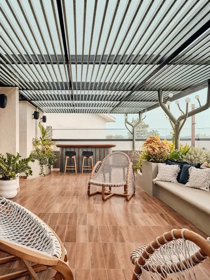 This spacious terrace is designed for relaxation and entertainment, featuring comfortable woven lounge chairs and a slatted pergola. It's a perfect example of how we extend the living area outdoors to create functional, beautiful spaces.