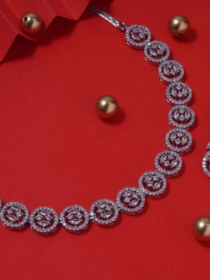 A simple and elegant AD stone necklace set with matching earrings, displayed on a festive red background. This versatile set can be worn for many different occasions.