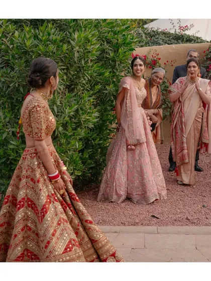 The bride's sister, mother, and grandmother see her in her bridal outfit for the first time. Their expressions of awe and emotion make this a priceless family moment.