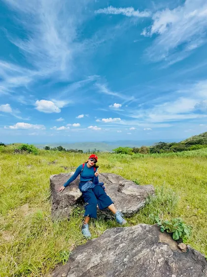 A trekker relaxing on a rock, enjoying the clear blue sky.