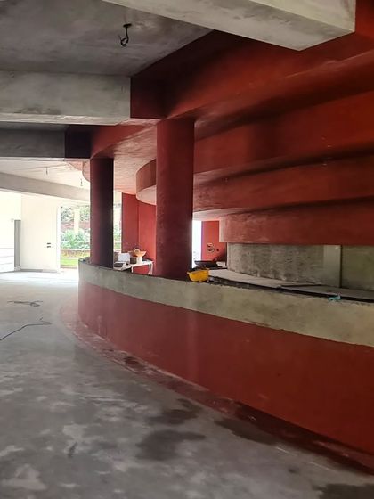 The vibrant red oxide plasterwork in progress at the TAPMI Centre, creating a bold, monolithic form that defines the interior space.