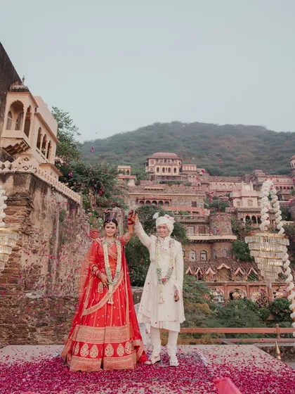 A truly royal affair at Neemrana Palace. This shot captures the majestic scale of a destination wedding, with the couple standing victorious on a carpet of rose petals against the historic fort.