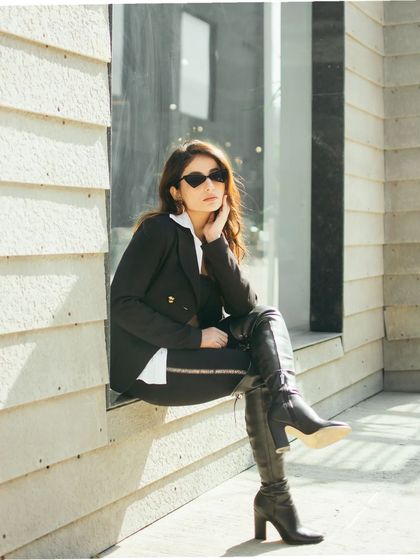 A seated pose from the same urban location, using the window ledge as a natural prop. This composition creates a more relaxed but still very chic and stylish street portrait.