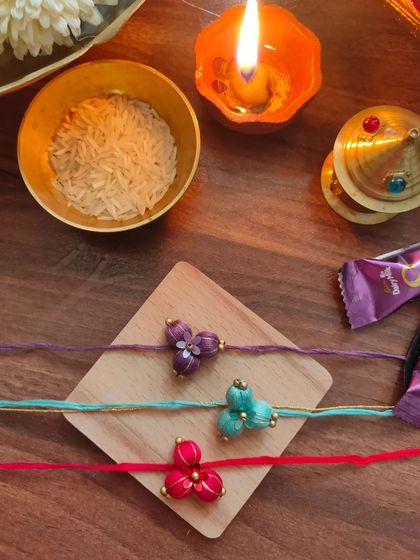 These beautiful floral rakhis are made from fabric beads and come in purple, teal, and red. Each one is carefully crafted by hand.