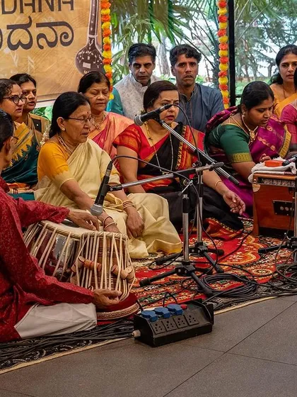 The entire group of musicians and singers gathered for a Kirtan session. The energy in the room is one of shared devotion and joy, created by the collective practice of chanting.