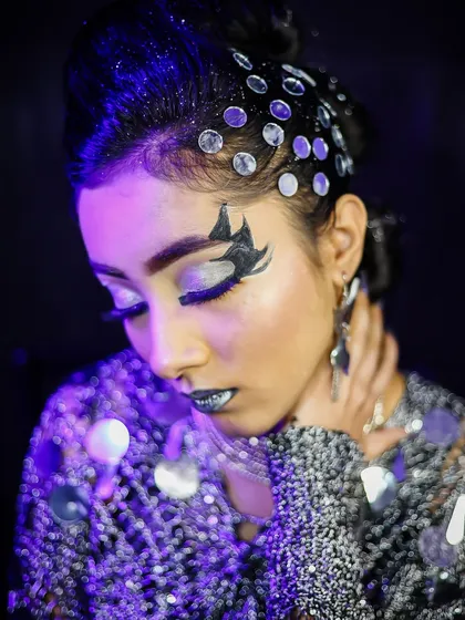 A close-up of the futuristic glam look, showing the mirror-like embellishments along the hairline and the sharp, winged eyeshadow.