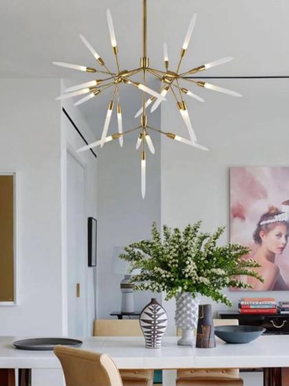 A modern starburst chandelier installed in a bright and airy dining room, serving as a stunning focal point.