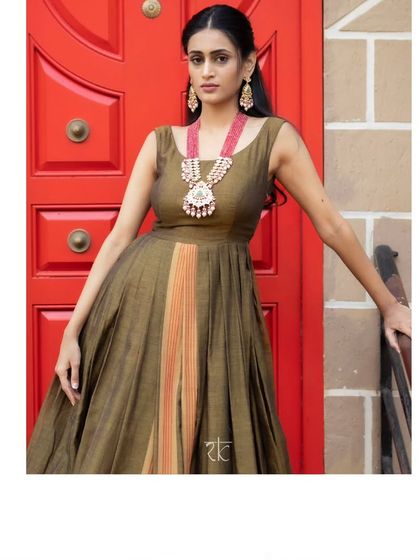 This caramel brown dress with a traditional silk border is a study in understated elegance. It is paired with a vibrant orange hand-embroidered jacket.