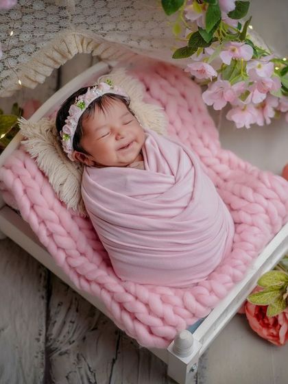 A smile in her sleep. This baby is dreaming sweet dreams, wrapped in pink and surrounded by a canopy of flowers.