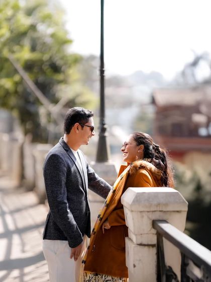 A bright, sunlit moment of shared laughter between Atul and Rachita on a bridge. This is a classic example of a candid shot where the couple is completely absorbed in each other, forgetting about the camera.