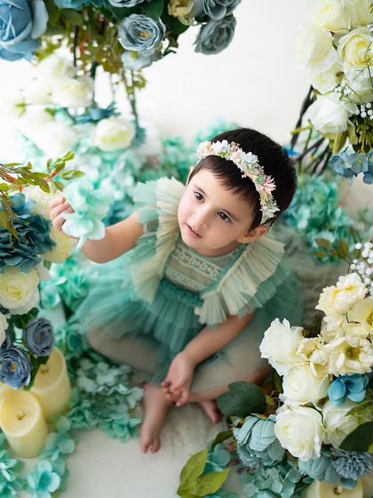 Looking up with curiosity at the floral arrangements during her tea party themed shoot.