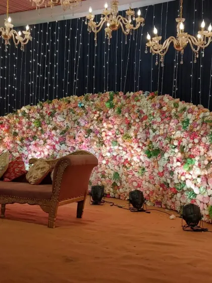 We designed this stage with a massive wall of pastel-colored flowers as the backdrop. The setup is accented with a black fairy light curtain and crystal chandeliers, providing a beautiful contrast and a touch of glamour.