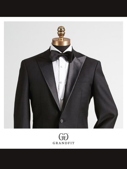A detailed view of the tuxedo's upper portion, focusing on the texture of the fabric and the sheen of the satin lapel against the crisp formal shirt.