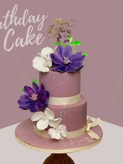 Let the lilac vibes brighten up your birthday bash! This two-tiered cake in a lovely shade of mauve is decorated with beautiful, handcrafted purple and white sugar flowers.