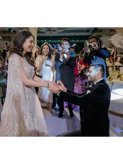 Raghav goes down on one knee to put a ring on Sanjana's finger. The surprise and joy on her face, along with the cheering crowd, make this a perfect proposal moment.