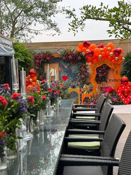 A view of the guest seating at the "Little Cutie" baby shower, with individual floral arrangements lining the long table. This ensures the decor extends beyond the main backdrop and is enjoyed by all attendees.
