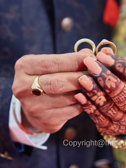 A detailed close-up of the couple's hands showcasing their engagement rings. This shot emphasizes the intricate henna on the bride's hand and the symbolism of the rings.