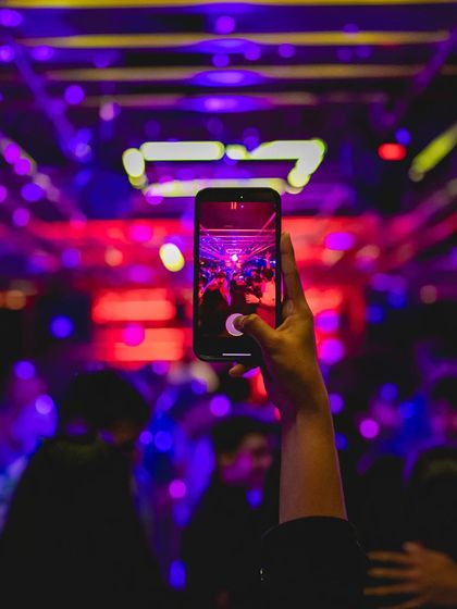 A partygoer capturing the moment on their phone. My events are filled with Instagrammable moments, from the lighting and decor to the energy of the crowd.