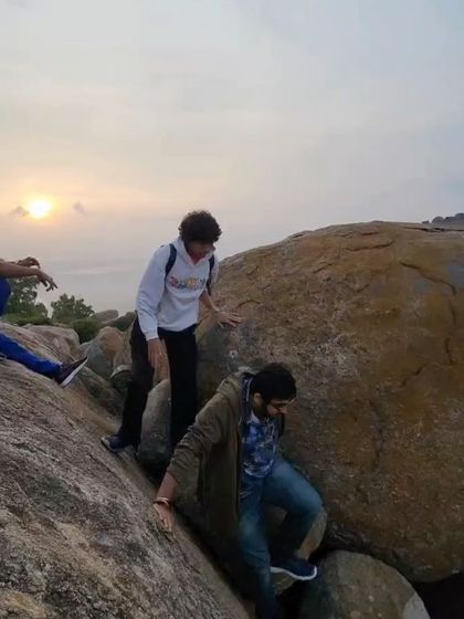 Trekkers scrambling over boulders on the Makalidurga trail as the sun rises.