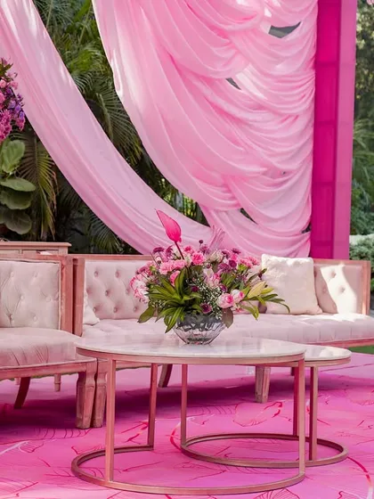 A lounge area with pink velvet sofas set against a custom pink-patterned floor, under dramatic pink drapes.