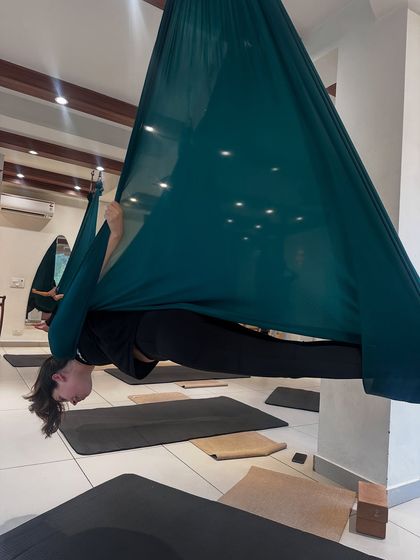 A student gracefully executes a split within the aerial hammock, showcasing incredible flexibility and control. The silk provides the necessary support to explore such advanced postures safely.