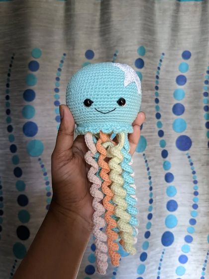 The pastel jellyfish held up against a blue and white background.