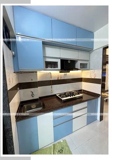 A completed modular kitchen in a 1BHK apartment. The combination of light blue and white acrylic cabinets creates a cheerful and modern cooking environment.