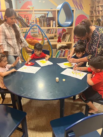 Teamwork makes the dream work. Here, two instructors are helping a group of toddlers with their painting project, ensuring everyone feels supported and included in the fun.