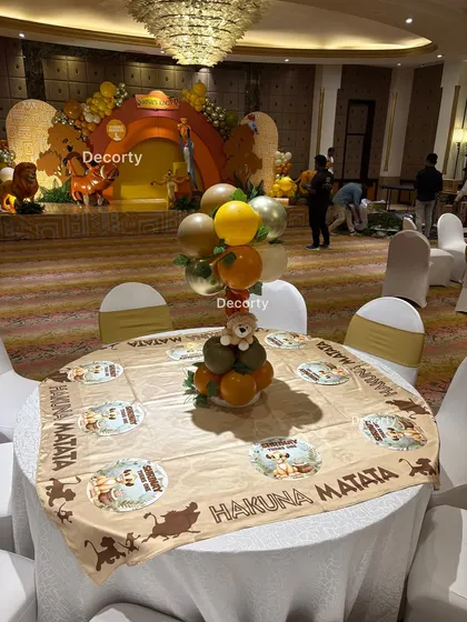 A full view of a guest table, showcasing the "Hakuna Matata" tablecloth and the balloon centerpiece that adds height and color to the room.