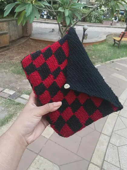 Holding my handmade checkerboard book sleeve. It's perfect for keeping your paperbacks safe in your bag. This red and black pattern is a fave, but I can make it in any color combo you want.