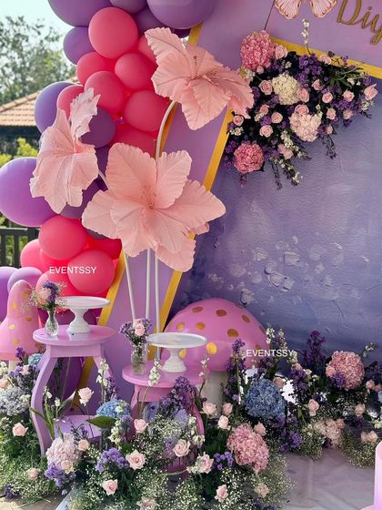 A detailed view of the oversized paper flowers and fresh floral arrangements, showcasing the mix of textures and shades of pink and purple.