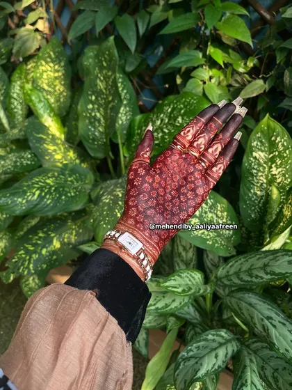 A beautiful, dark stain on a hand against a lush green background.