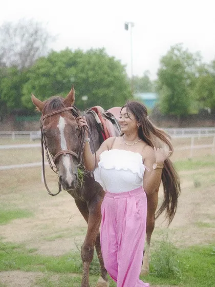 A woman stands with her horse, holding the reins gently. This image portrays the partnership and companionship that is central to horse riding.