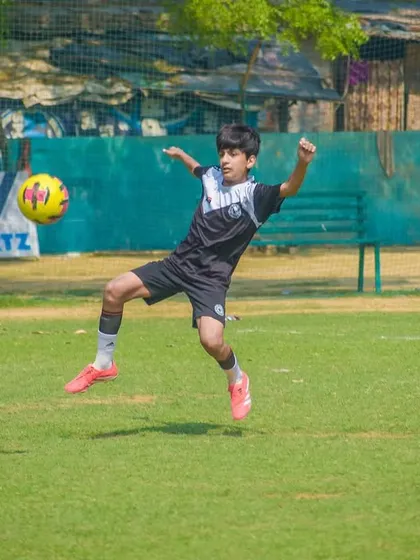 A player leaps into the air to control the ball, displaying impressive athleticism and coordination on the field.