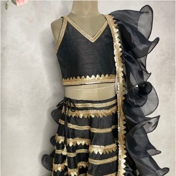 A full view of the black and gold lehenga, emphasizing the movement and drama of the ruffled organza dupatta.